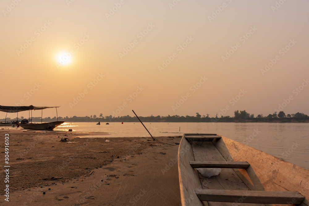 A boat on a sandy beach at sunset