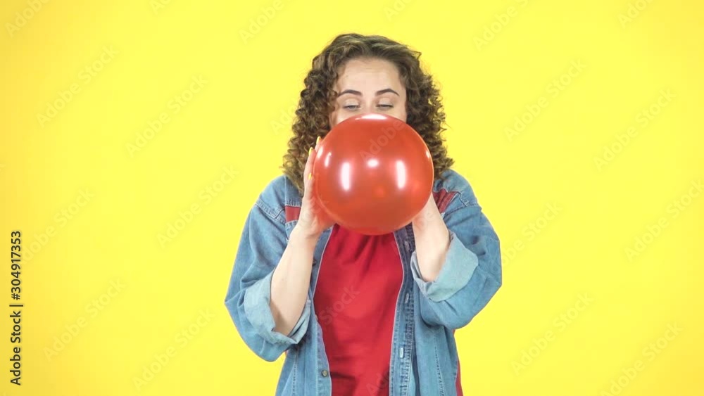 The girl inflates a red balloon, takes in hand and releases, the ball is blown away and flies away, slow motion The girl inflates a red balloon, takes in hand and releases, the ball is blown away and flies away, slow motion