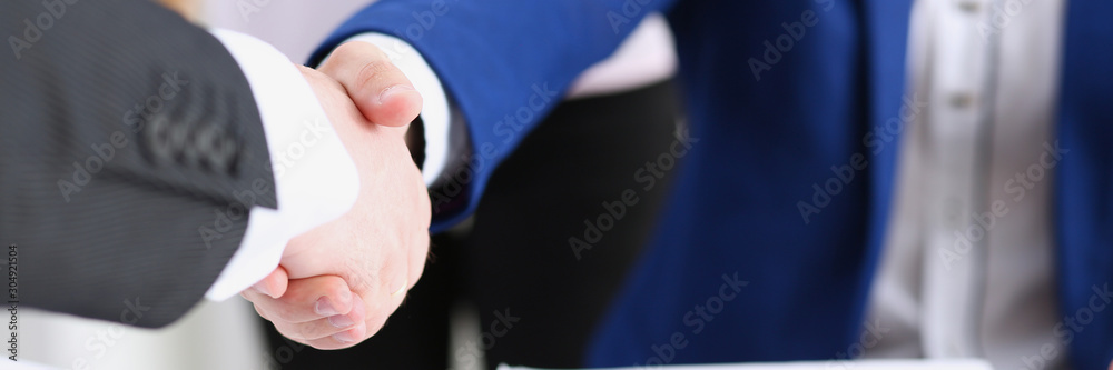 Man in suit shake hand as hello in office closeup