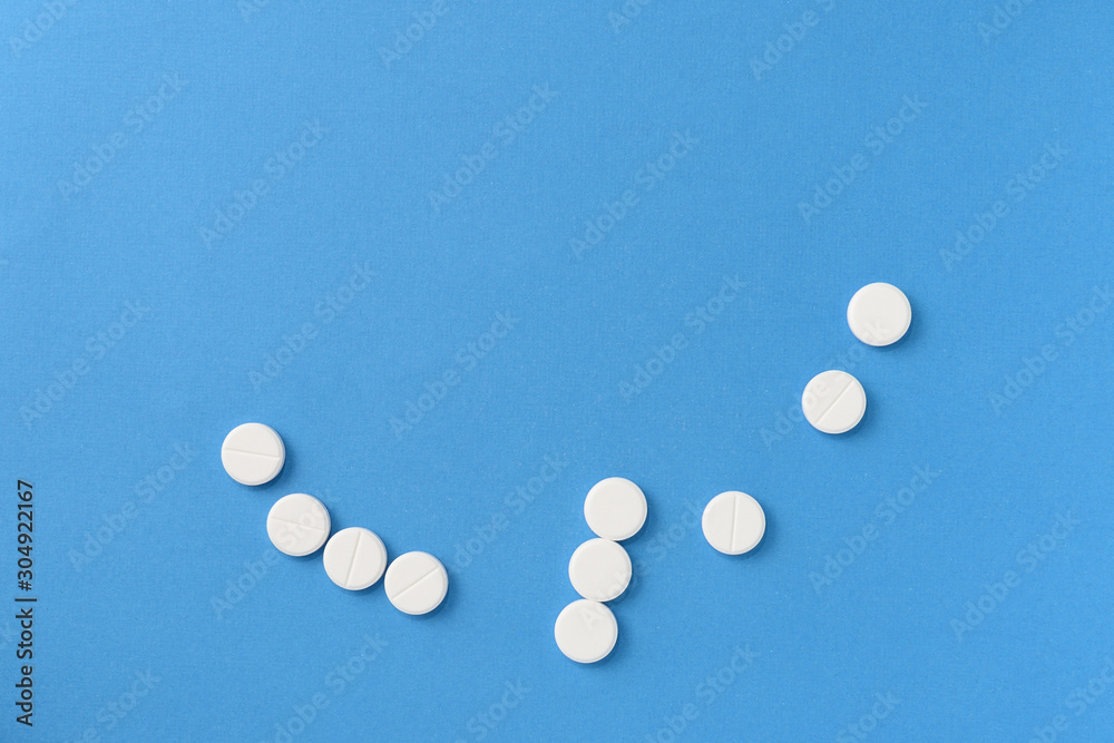 White round pills scattered on a blue background, top view. Medical pharmacy concept White round pills scattered on a blue background, top view. Medical pharmacy concept