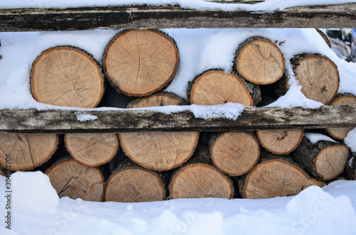 Logs of firewood covered with snow after a snowfall Christmas or winter weather storm scenic concept