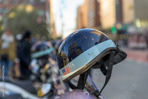 Police helmet with American flag sticker hanging off a police scooter on a New York City street