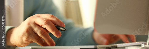 A young designer holds a pen from a tablet in his
