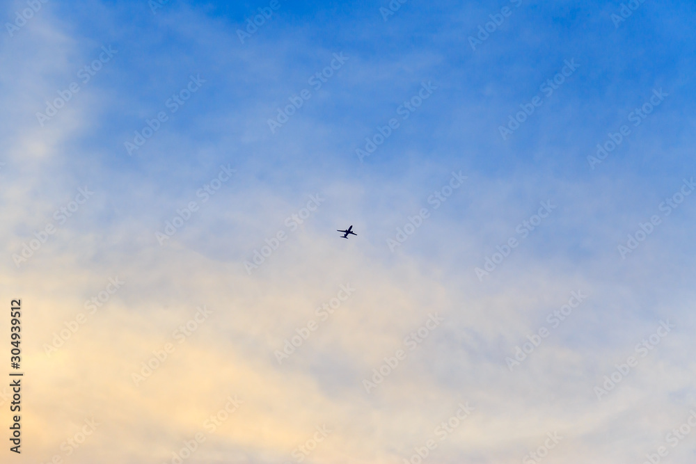 Unspecified small plane on the blue sky and clouds