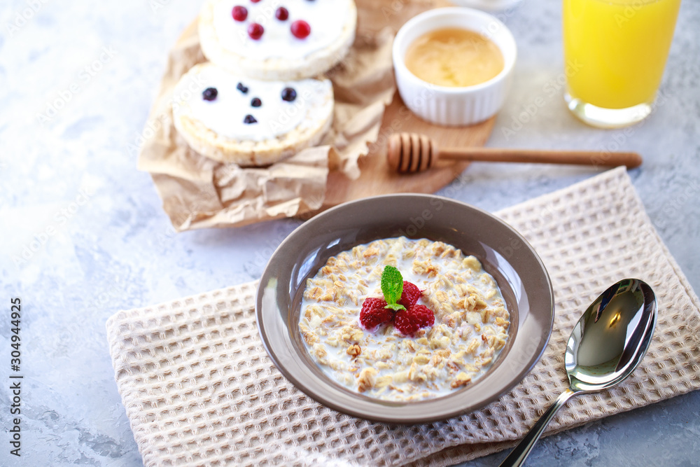 Baked granola with milk and raspberries in a plate, whole grain breads and freshly squeezed juice. A wholesome and dietary breakfast. Delicious muesli Baked granola with milk and raspberries in a plate, whole grain breads and freshly squeezed juice. A wholesome and dietary breakfast. Delicious muesli