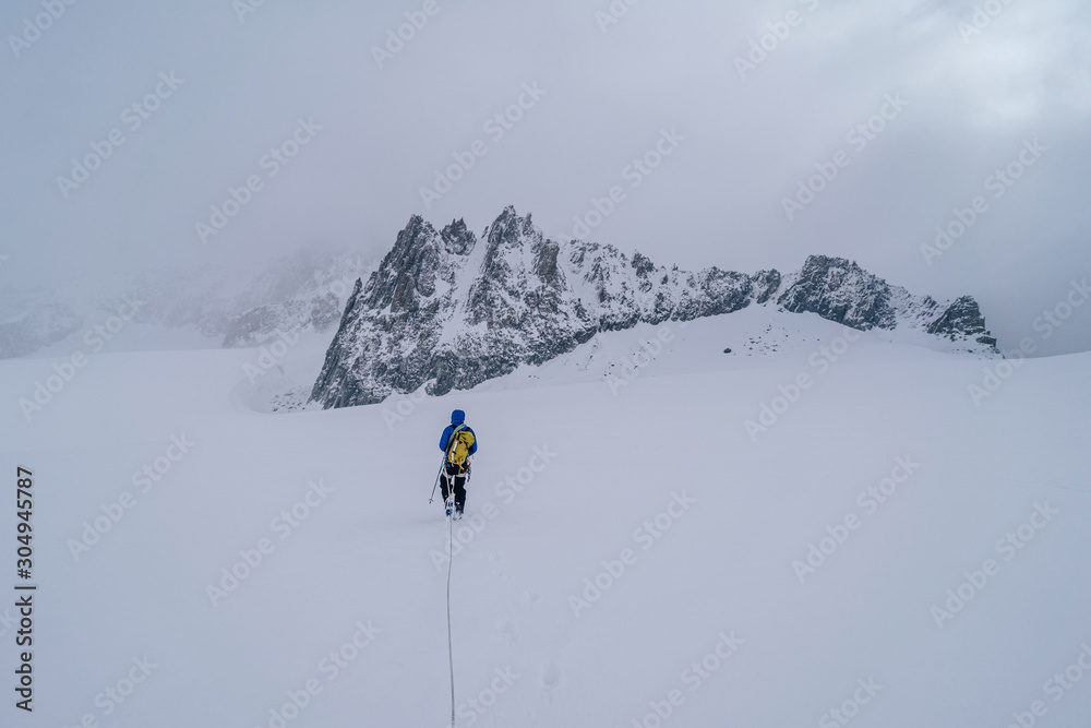 An alpinist walking on a glacier using rope. Detail shot of a climber with a rope in extreme mountain conditions. Adventure ascent of an alpine peak.