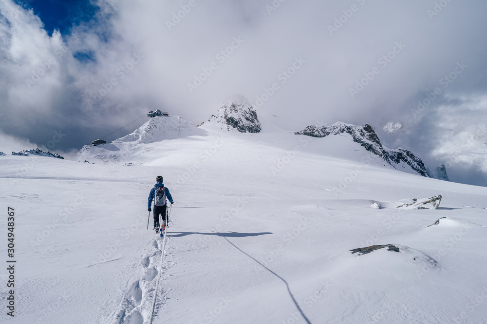 Climbers walking on a glacier using rope and ice axe. Alpinist in high alpine mountain landscape, walking in snow. Adventure outdoor activity.