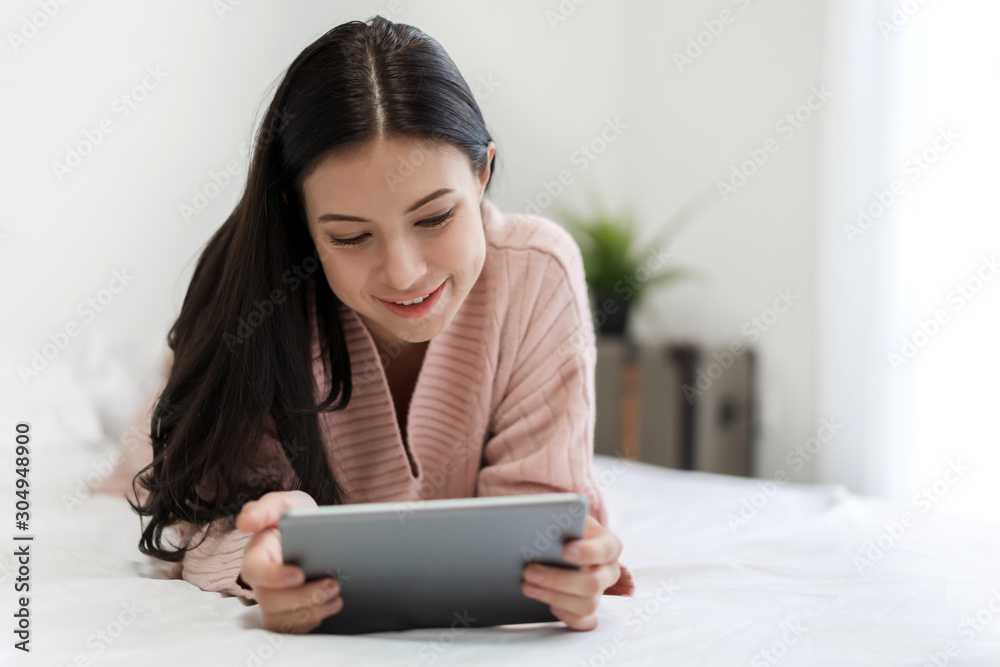 Happy woman relaxing using tablet computer on the bed at home.technology and communication concept Happy woman relaxing using tablet computer on the bed at home.technology and communication concept