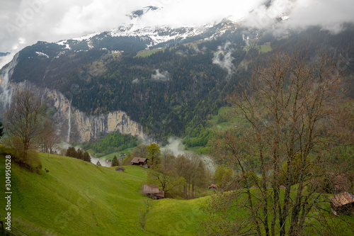 Charming scene of fresh green field with wooden houses on mountain for background with copy space, Switzerland