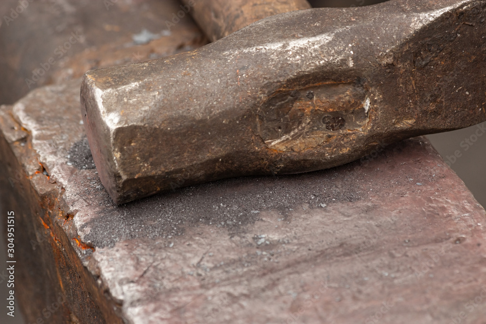Old rusty hammer lies on the anvil. Blacksmith, metalsmith, farrier tools. Close view. Old rusty hammer lies on the anvil. Blacksmith, metalsmith, farrier tools. Close view.