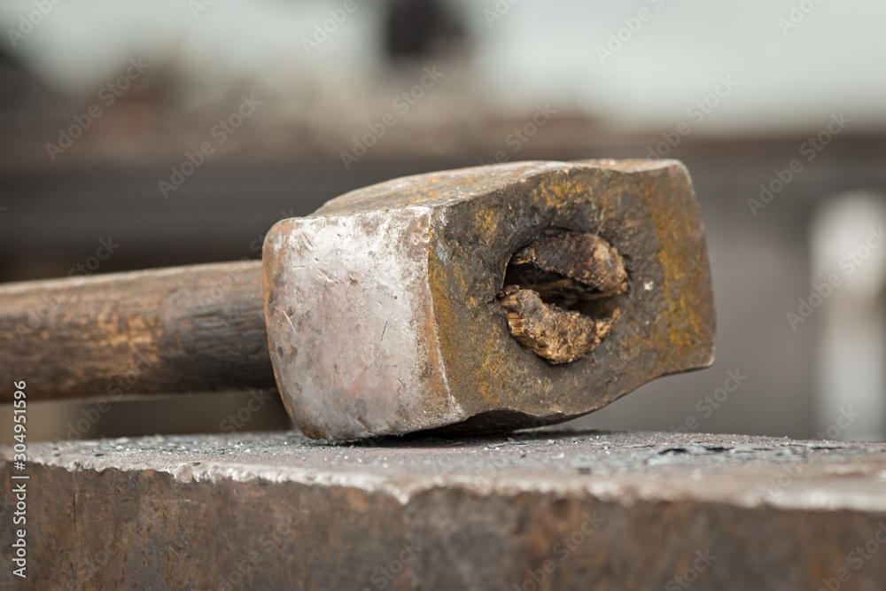 Old rusty hammer lies on the anvil. Blacksmith, metalsmith, farrier tools. Close view. Old rusty hammer lies on the anvil. Blacksmith, metalsmith, farrier tools. Close view.