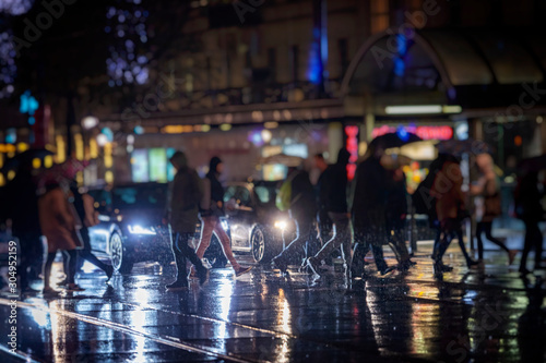 pedestrians crossing street on rainy night in the city