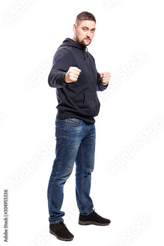 A young man in jeans in a fighting stance. Full height. Isolated over white background. Vertical.