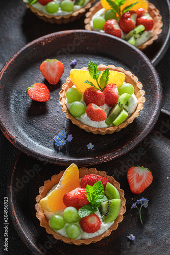 Tasty mini tart with fresh fruits, mint and whipped cream