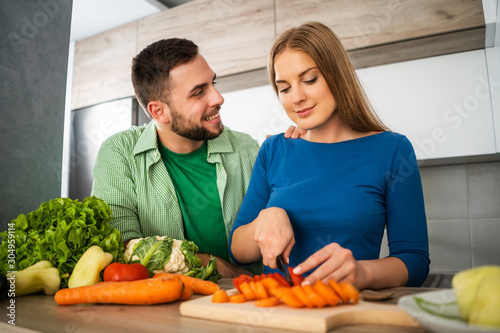 Young couple is preparing meal in their kitchen.