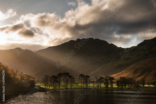 Majestic vibrant Autumn Fall landscape Buttermere in Lake District with beautiful early morning sunlight playing across the hills and mountains photo