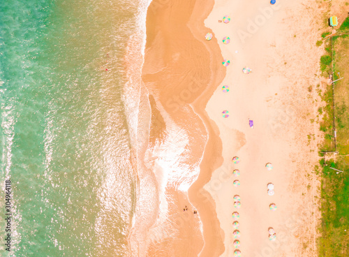 Aerial top down beach view with DRONE in Montanita. Dramatic view of the turquoise ocean, orange sand, tourist sunbathers and waves. Shot in Ecuador. Scenic, holiday, tourism shot. Umbrellas and sunbe