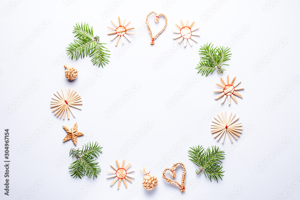 Obraz premium Christmas round frame with fir tree branches, wooden decorations, confetti on grey background, copy space. Round frame with eco decorations and green branches