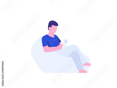 Young man sitting on beanbag chair and reading book