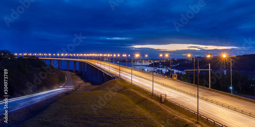 Panoramic twilight view of the bridge with traffic light trails and cloudy sky