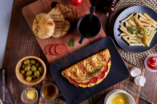 Pepperoni omelette in black plate on wood table