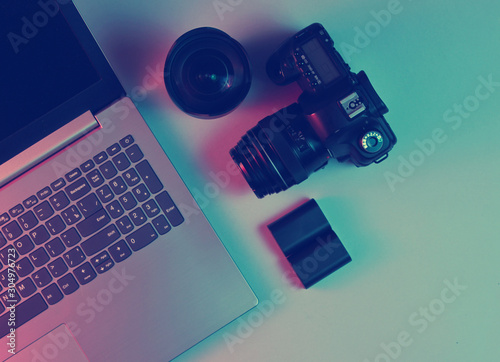 Equipment professional photographer. Laptop, camera, lenses. Neon light. Top view