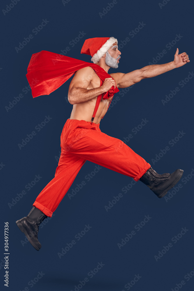 Nude Santa Claus jumping up with sack full of presents Stock Photo
