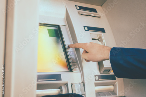 Close-up of man using ATM in the city.
