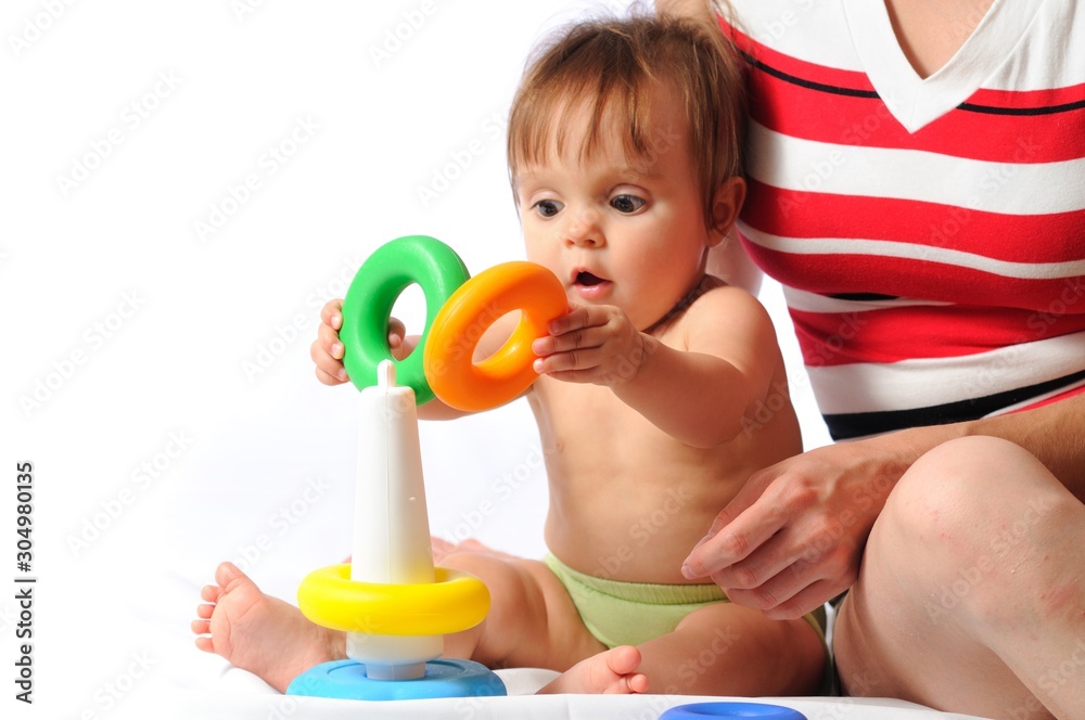 Funny training play of colorful pyramid with loved mother. Little baby sitting and playing toy with parent. Isolated on white background Funny training play of colorful pyramid with loved mother. Little baby sitting and playing toy with parent. Isolated on white background
