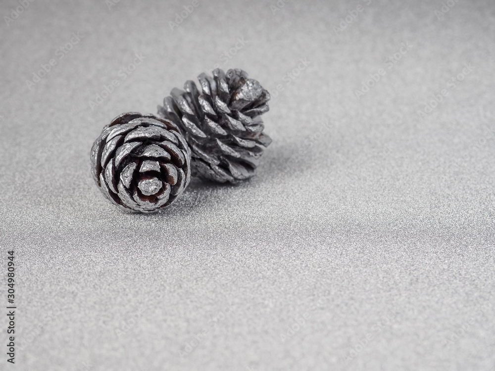 Silver pine cones on white wooden background. White and silver pallet. Chrstmas greeting card. The object of the celebration with free space for text. Silver pine cones on white wooden background. White and silver pallet. Chrstmas greeting card. The object of the celebration with free space for text.