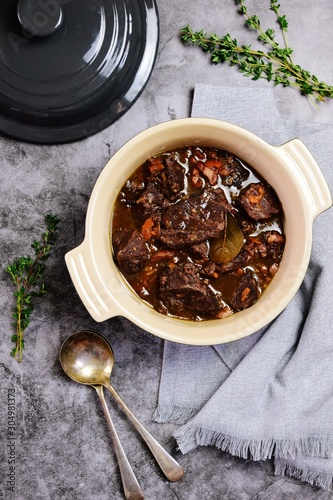 Beef bourguignon in the pot on the grey background, top view
