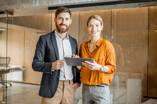 Portrait of a two colleagues standing together with digital tablet in creative studio. Work in marketing agency or design studio concept photo