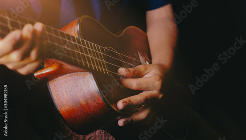 Hands playing acoustic ukulele guitar.Music skills show photo