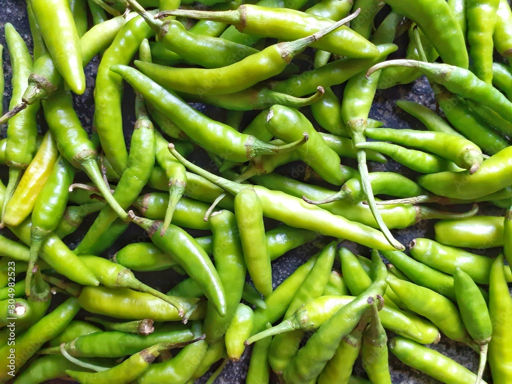 Green chillies background. Closeup image of peppers on the floor. Green chillies background. Closeup image of peppers on the floor.