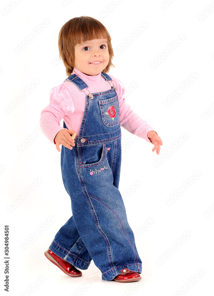 Small girl in jeans jumpsuit walking and smiling Small girl in jeans jumpsuit walking and smiling