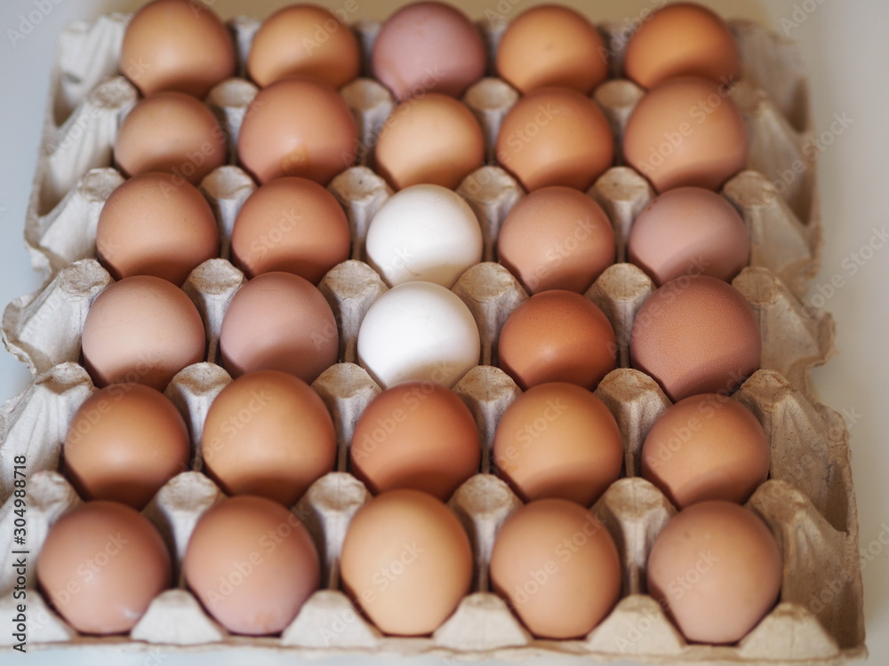 brown eggs and two white eggs in a wooden storage container