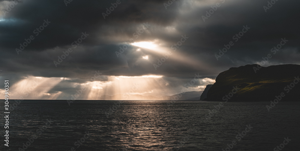 Beautiful rays of sun breaking through the clouds in Sandoy and Hestur ferry travel, Faroe Islands