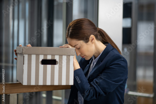 Dark-haired woman wearing dark jacket feeling awful after losing her job