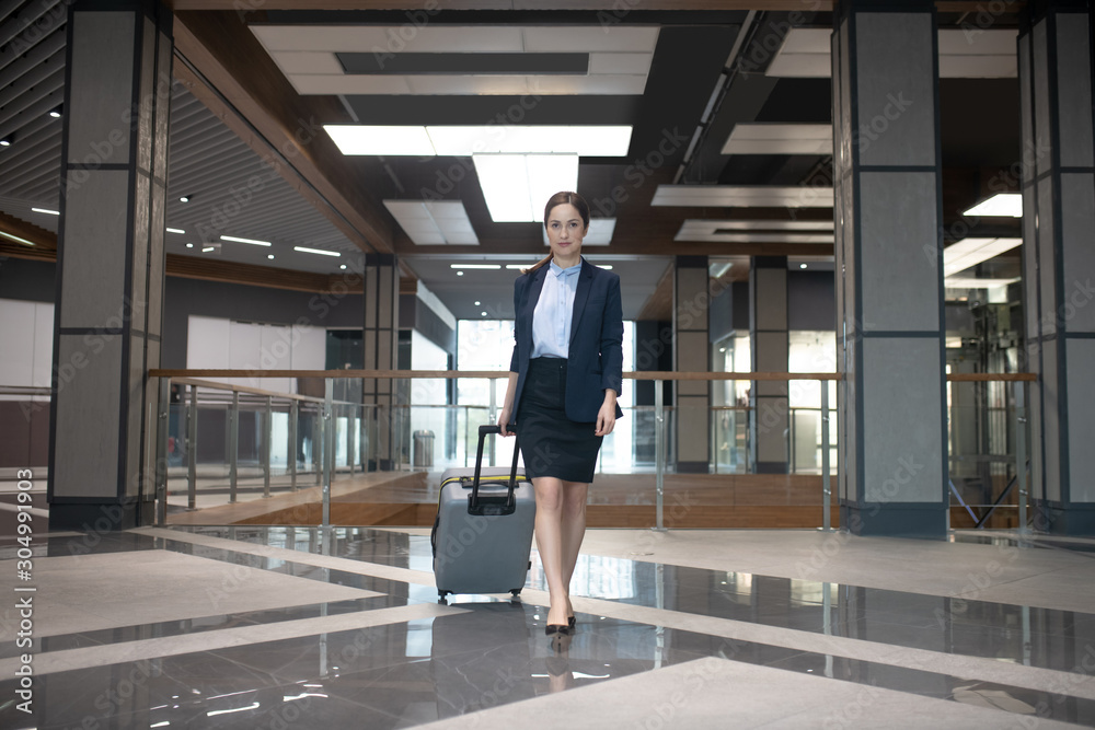 Elegant businesswoman walking with her luggage while having business trip