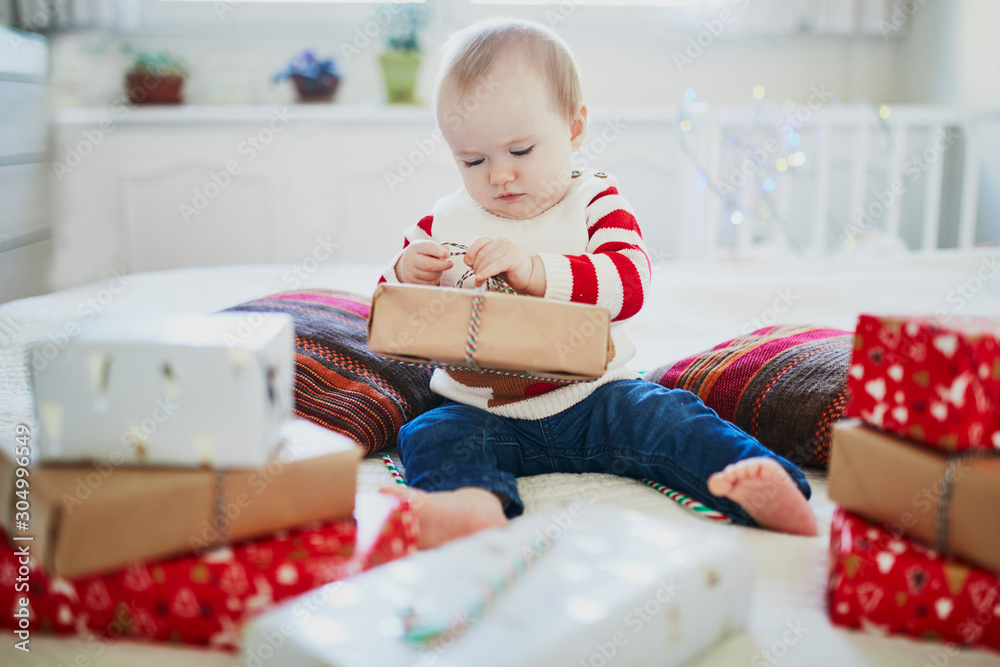 Happy little baby girl opening Christmas presents on her very first Christmas Happy little baby girl opening Christmas presents on her very first Christmas