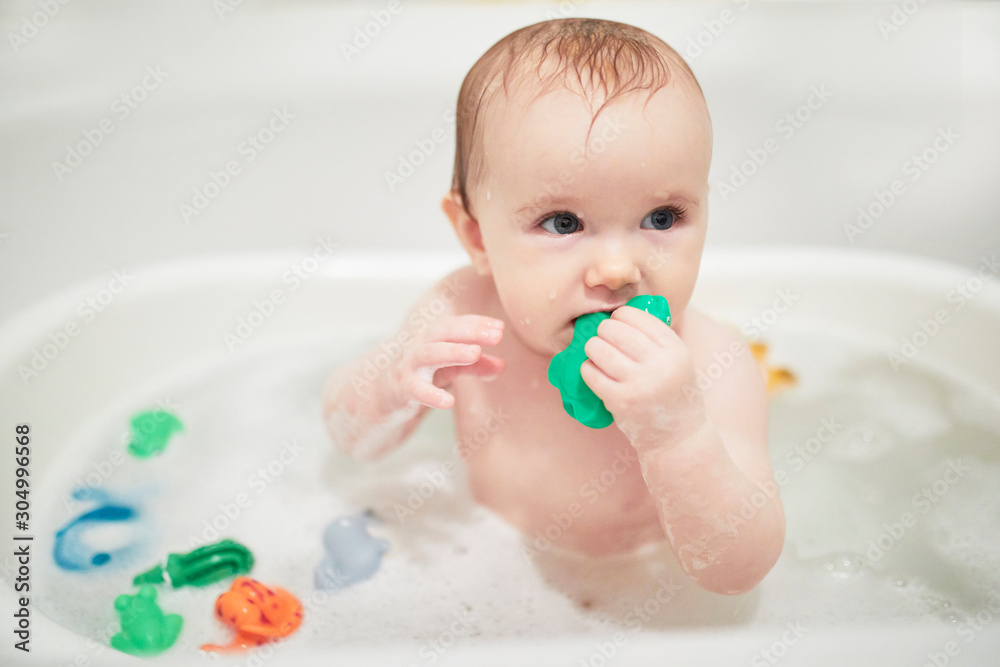 Cute little girl playing with rubber toys in small bathtub Cute little girl playing with rubber toys in small bathtub