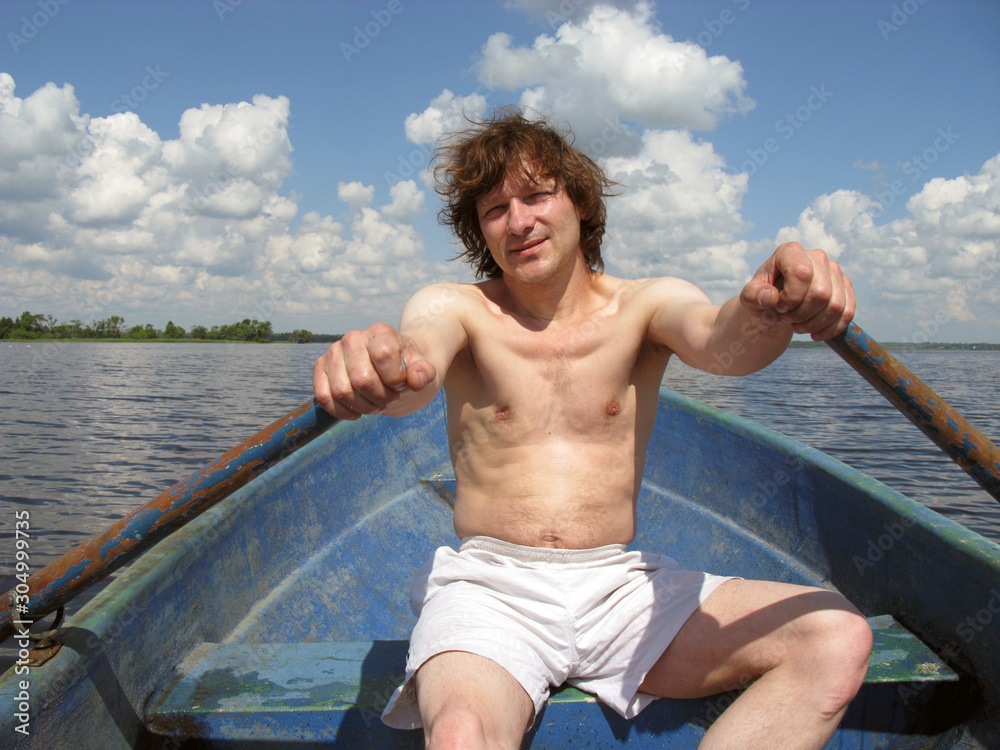 A man rowing oars in a boat at sunset. Russia. Volga river