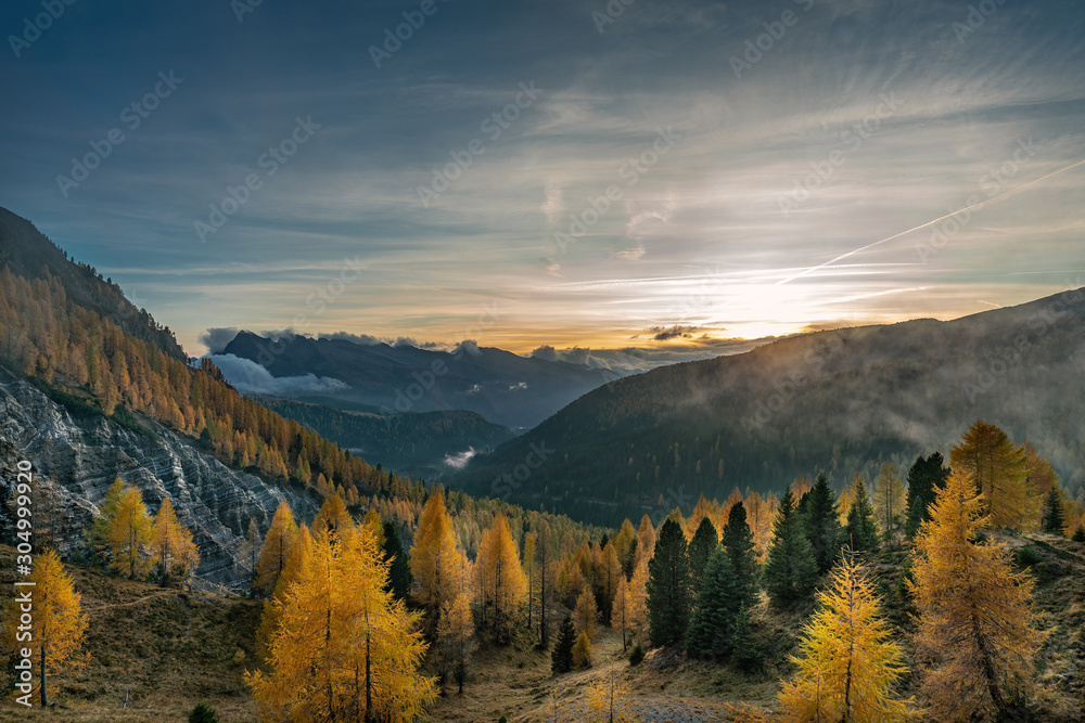 Sunset on a foggy autumn evening overlooking the valley of the Valles pass in South Tyrol