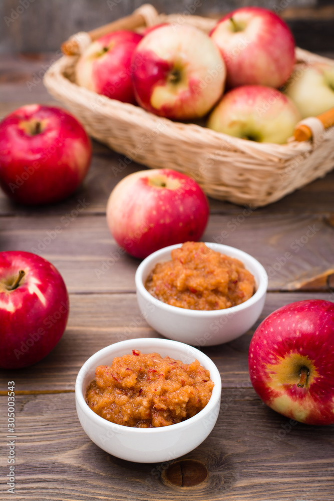 Fresh applesauce in bowls and red apples on a wooden table Fresh applesauce in bowls and red apples on a wooden table