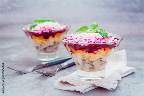 Traditional Russian appetizer of boiled vegetables and fish - a herring under a fur coat in bowls on the table. Russian salad