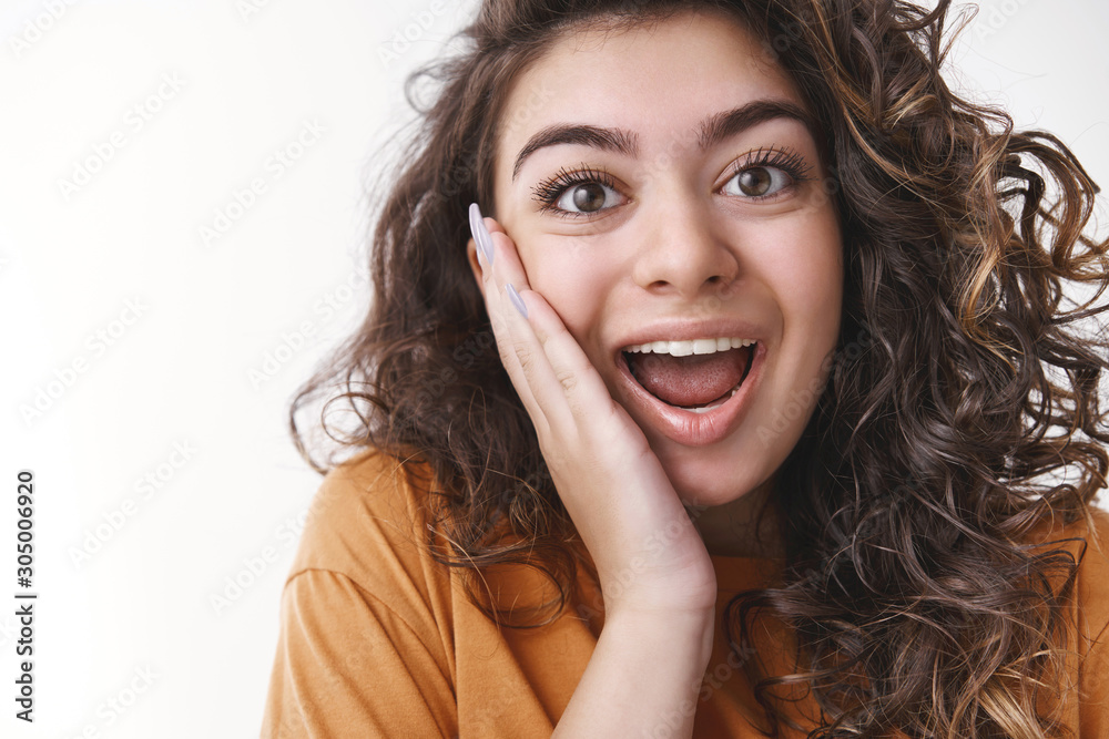 Wondered amazed good-looking young charming woman curly hair widen eyes open mouth happily reacting awesome cool surprise touch cheek impressed standing joyfully white background Wondered amazed good-looking young charming woman curly hair widen eyes open mouth happily reacting awesome cool surprise touch cheek impressed standing joyfully white background