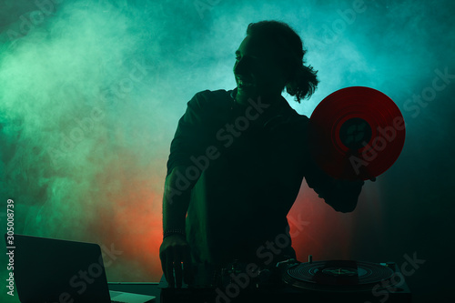 Silhouette of male dj playi...