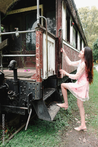 Young beautiful asian woman in pink dress relaxing with an old train