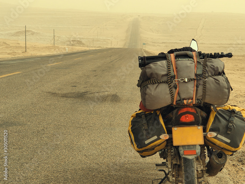 Motorcycle with travel baggage parked by the roadside in sandstorm weather