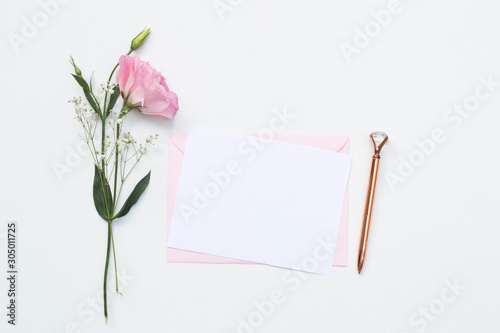 Flat lay shot of letter and eco paper envelope on white background. Wedding invitation cards or love letter with pink roses. Valentine's day or other holiday concept, top view, flat lay, overhead view